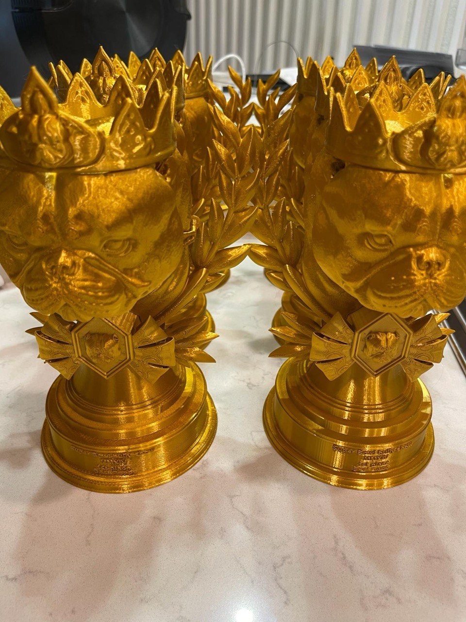 Batch of gold bulldog head crown trophies with laurel wreaths