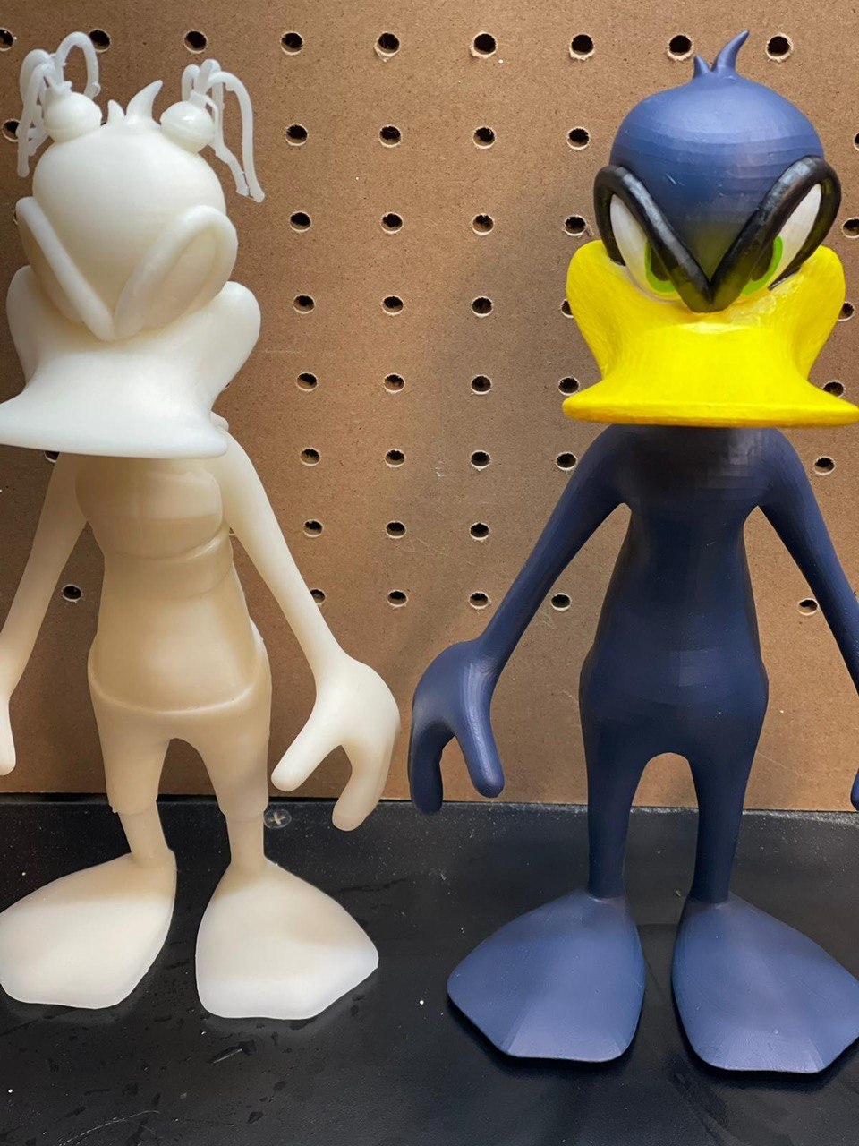 Raw white 3D print beside the same figure hand-painted in blue and yellow