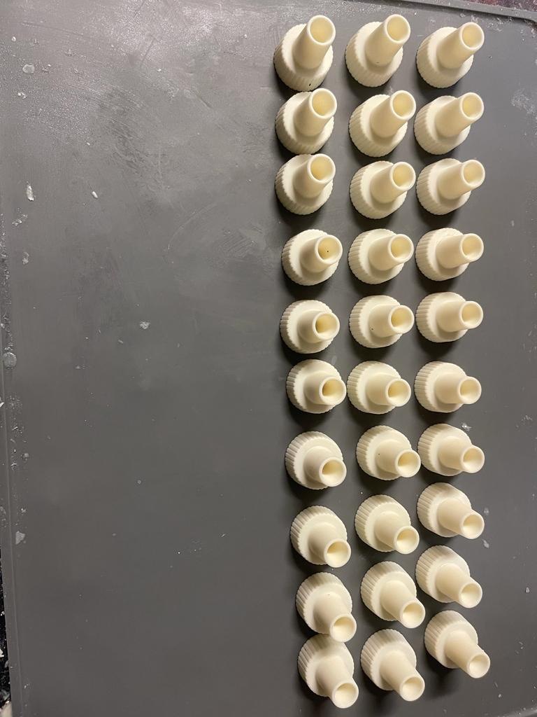 Grid of thirty cream 3D printed threaded nozzle adapter fittings