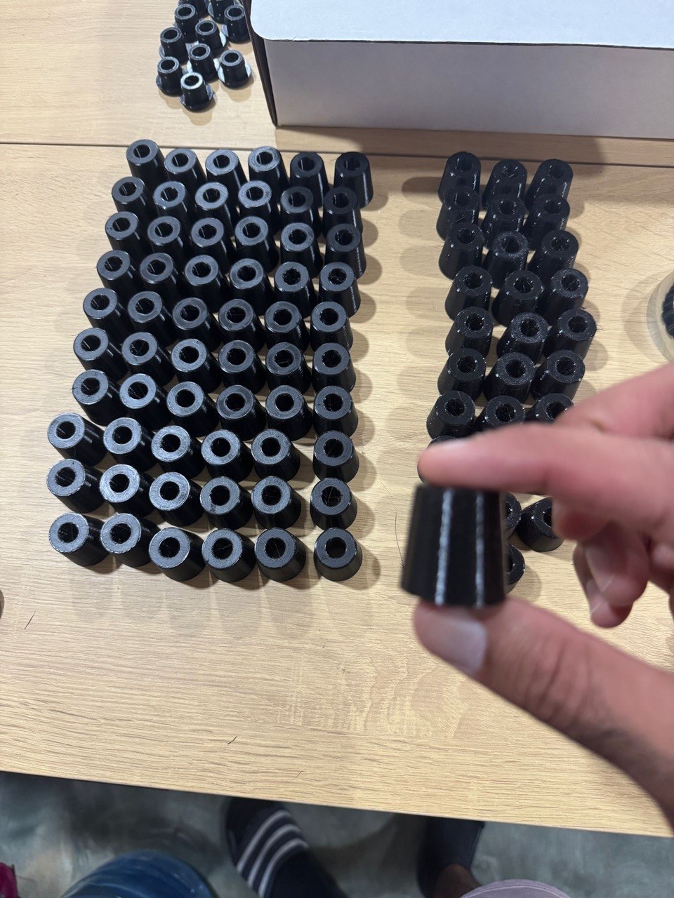 Production batch of about ninety black 3D printed cylindrical spacers